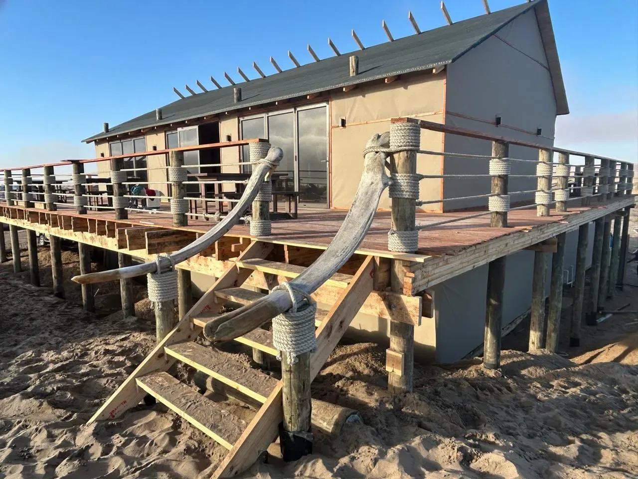 Whale-rib rails frame the timber steps up to a Meob Lodge cabin