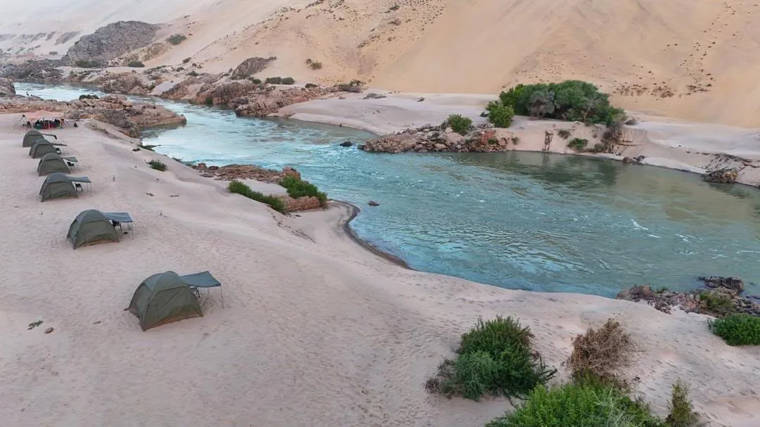 Camp on the white sand beside the Kunene's turquoise rapids